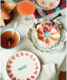 Assiette en porcelaine Rice avec des fleurs et le message "Merci" délicatement peint artisanalement au Portugal.