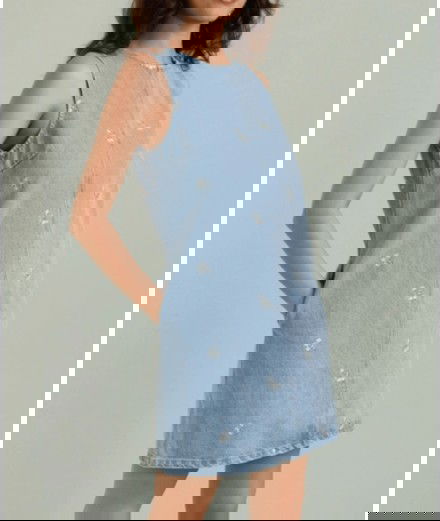 Robe en jean et avec de petites broderies en forme de fleurs.
