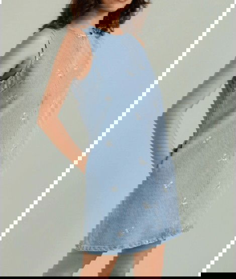Robe en jean et avec de petites broderies en forme de fleurs.